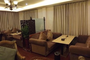 A hotel room with a sofa set, a small table, and a decorative plant.