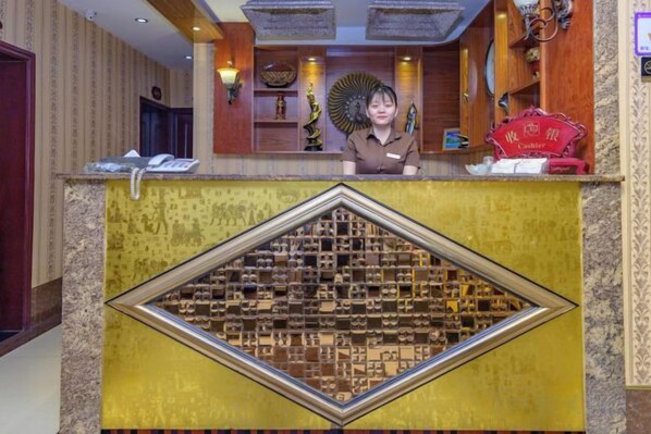 Una mesa de recepción con una pared decorativa, un teléfono y un letrero rojo.