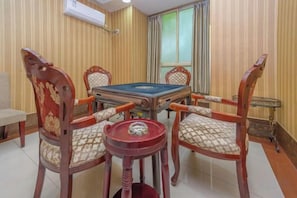 A pool table with four chairs, a small table, and a window with curtains.