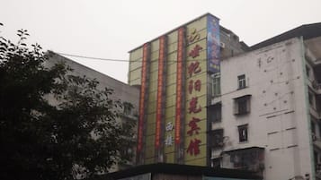 A multi-story building with vertical signage and a large advertisement on the lower level.