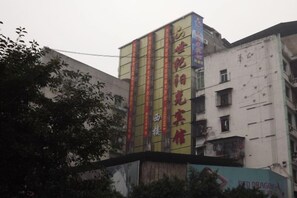 A multi-story building with vertical signage and a large advertisement on the lower level. - Quxian Century Sunshine Hotel-The West Hotel (Qu County)