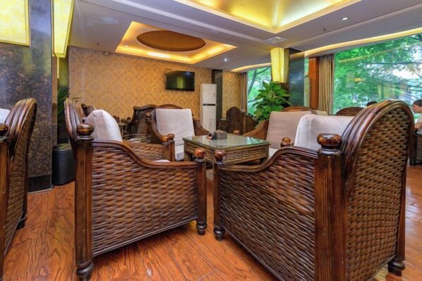 A room with wicker furniture, a flat-screen TV, and a view of greenery outside.