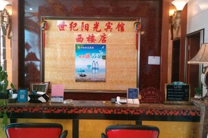A reception desk with a wooden panel, a framed poster, and a digital screen.