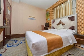 Ein Hotelzimmer mit Bett, Schreibtisch, Stuhl, Spiegel und einem fenster mit Vorhängen.