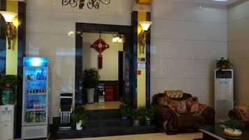 A lobby with a vending machine, a sofa, and a large air conditioning unit.