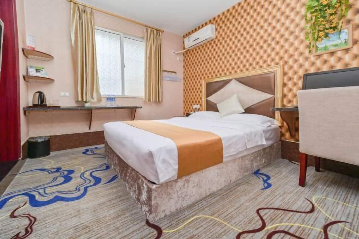 Ein Hotelzimmer mit einem Bett, einem Schreibtisch, einem Stuhl, einem fenster mit Vorhängen und einer Wand mit Muster.