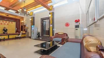 A hotel lobby with a reception desk, seating area, and a staircase.