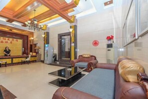 A hotel lobby with a reception desk, seating area, and a staircase.