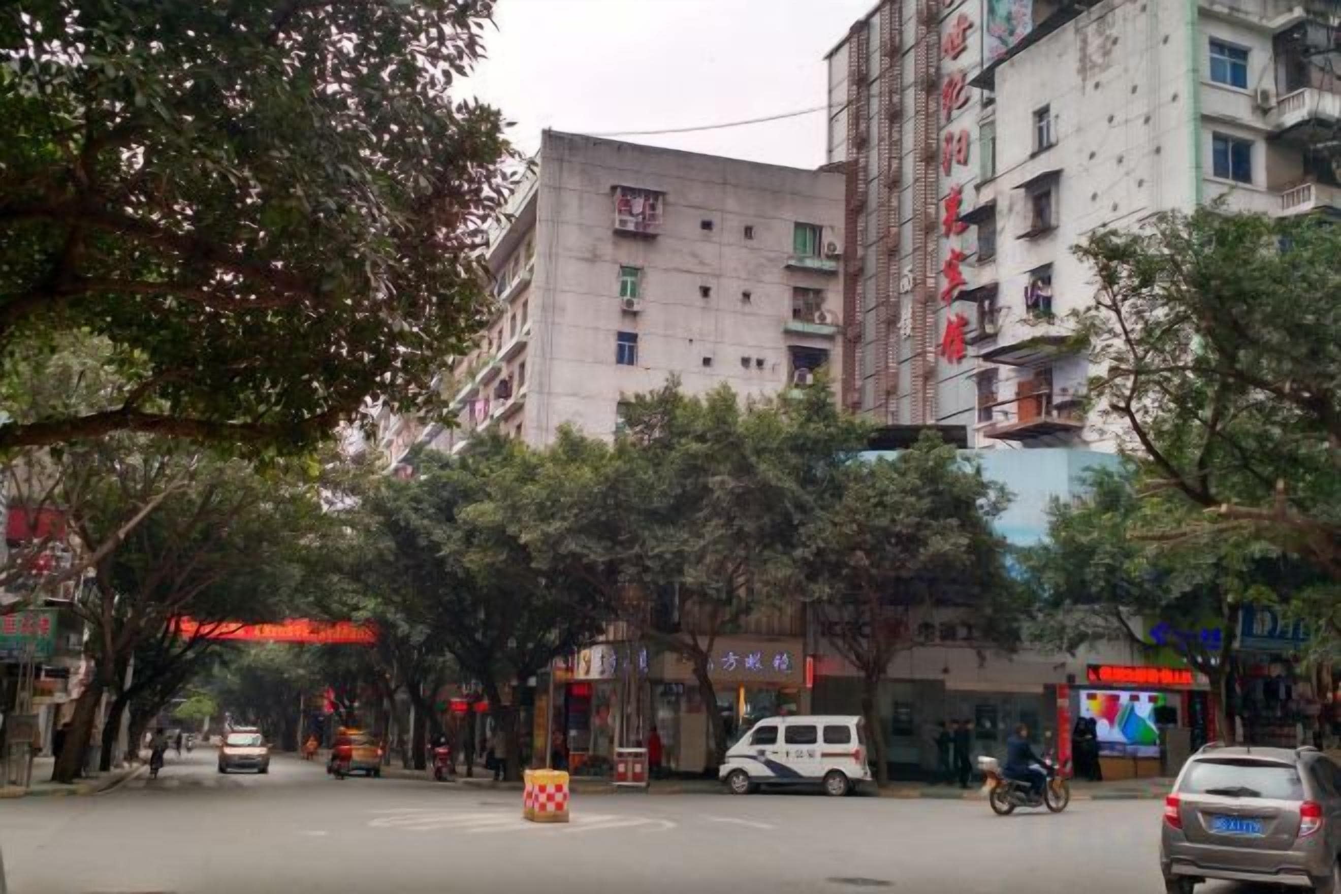 Une vue de rue avec des bâtiments, des arbres et des véhicules.