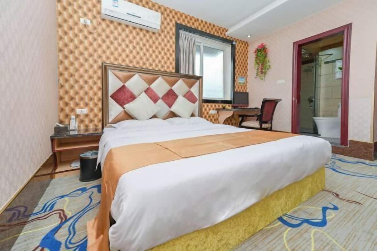 Ein Hotelzimmer mit Bett, Schreibtisch, Stuhl, Klimaanlage und Badezimmertür.