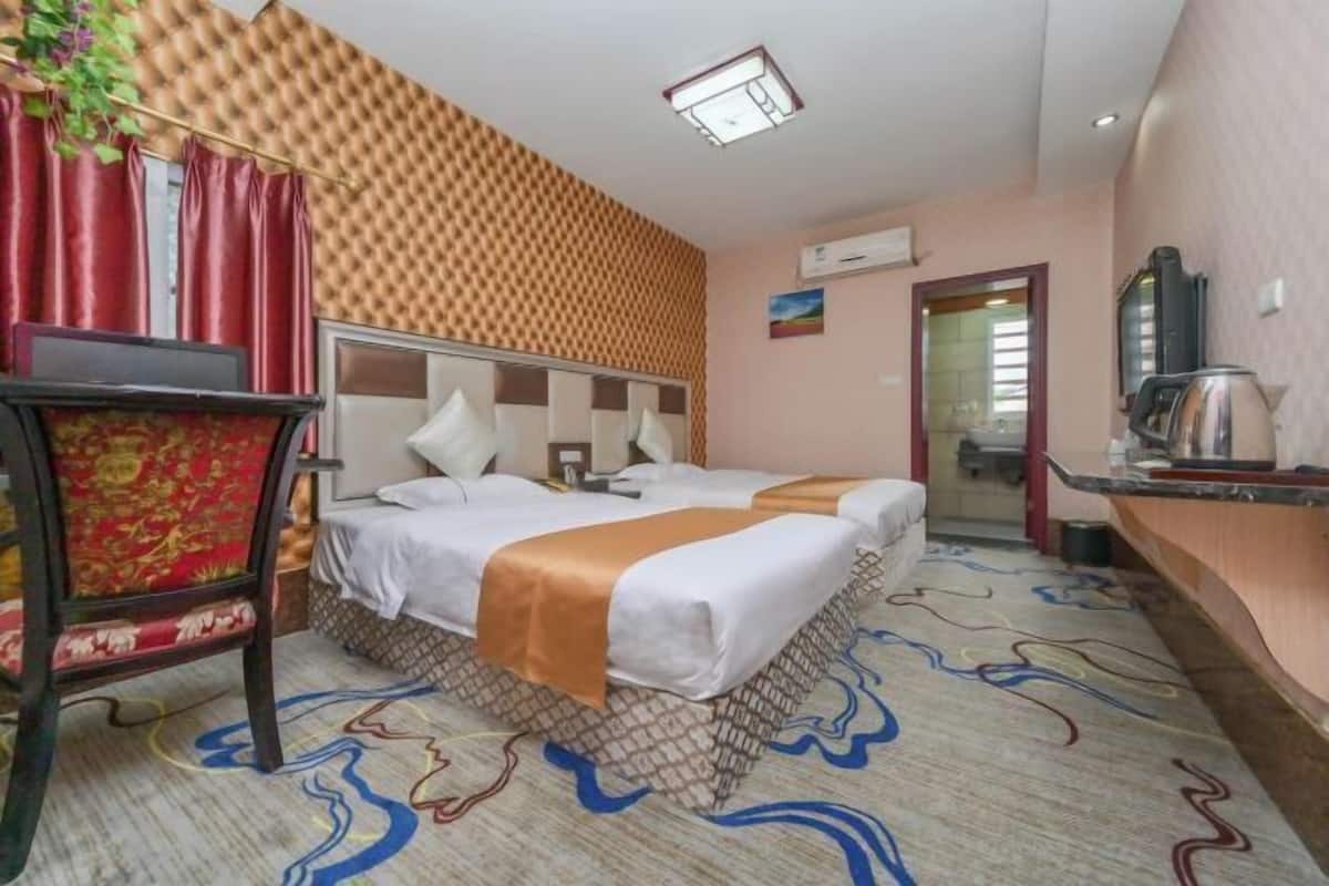 Ein Hotelzimmer mit Bett, Schreibtisch, Sessel, Fernseher und Kaffeemaschine.