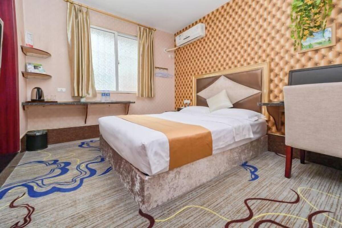 Ein Hotelzimmer mit Bett, Schreibtisch, Sessel, Klimaanlage und einer Wand mit Muster.