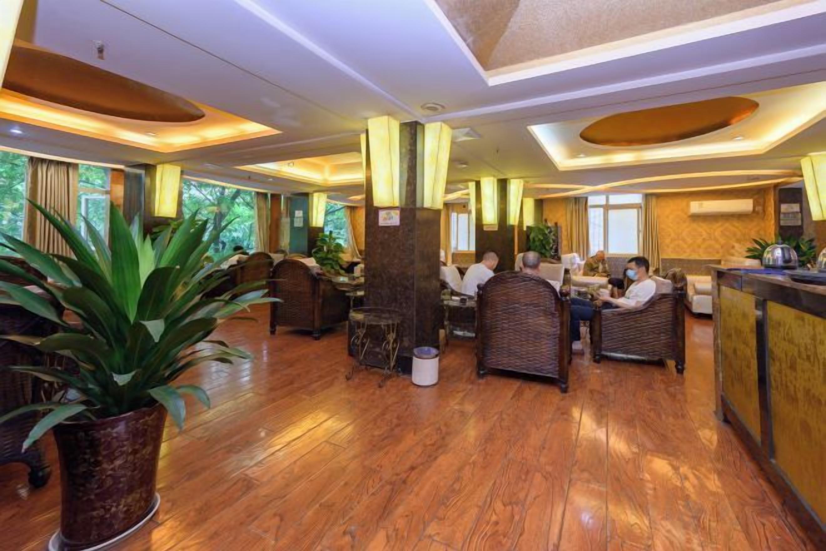 Un hall de hotel con suelo de madera, zonas de estar y un mostrador de recepción.