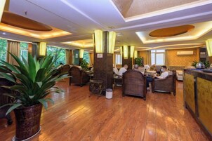 A hotel lobby with wooden flooring, seating areas, and a reception desk.