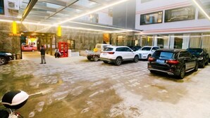 A hotel lobby with a wet floor, multiple cars parked inside, and a glass ceiling. - Quxian Century Sunshine Hotel-The West Hotel (Qu County)
