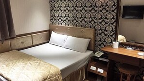Une chambre d’hôtel avec un lit, un bureau avec un téléphone, un miroir et un papier peint à motifs.