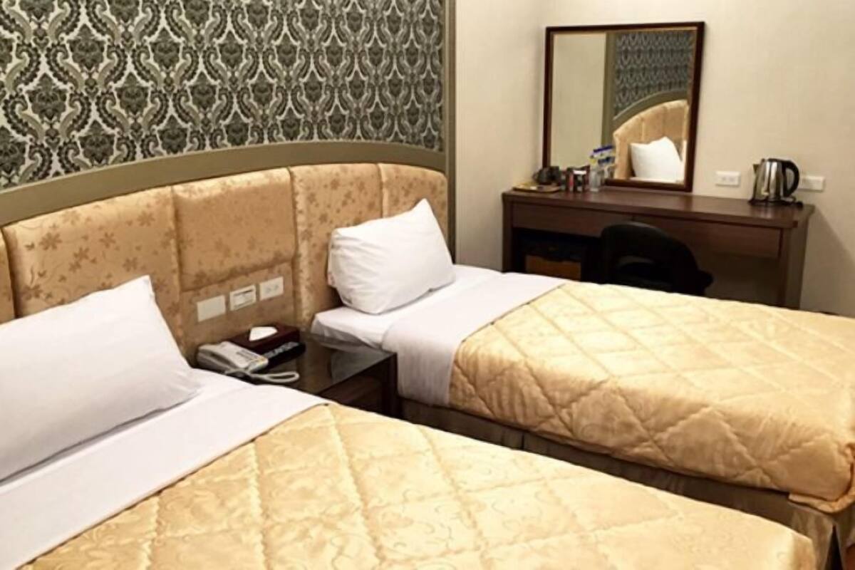 Een hotelkamer met twee bedden, een bureau, een stoel en een spiegel.