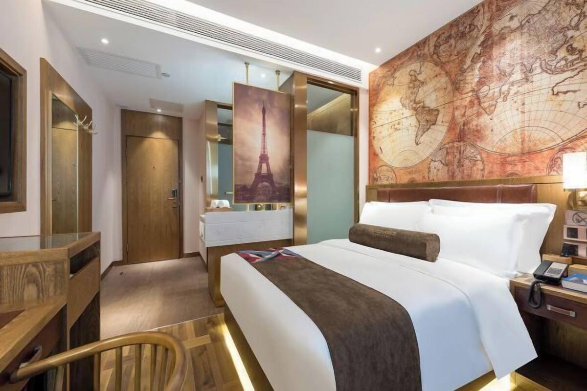 Una habitación de hotel con una cama grande, un escritorio, una silla, un armario y un mapa mural.