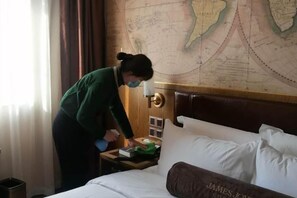 A hotel room with a neatly made bed, a wooden headboard, a nightstand with a lamp, and a wall map. - James Joyce Coffetel (Beijing Daxing Huangcun Qingyuan Road Metro Station branch) (Beijing)
