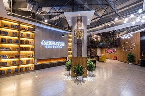 A modern interior with a coffee shop named 'James Joyce Coffee' featuring bookshelves, a central pillar, and a cozy seating area. - James Joyce Coffetel (Beijing Daxing Huangcun Qingyuan Road Metro Station branch) (Beijing)