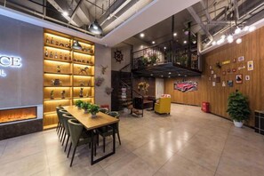A spacious hotel lobby with a wooden reception desk, a seating area with chairs, a fireplace, and a staircase leading to an upper level. - James Joyce Coffetel (Beijing Daxing Huangcun Qingyuan Road Metro Station branch) (Beijing)