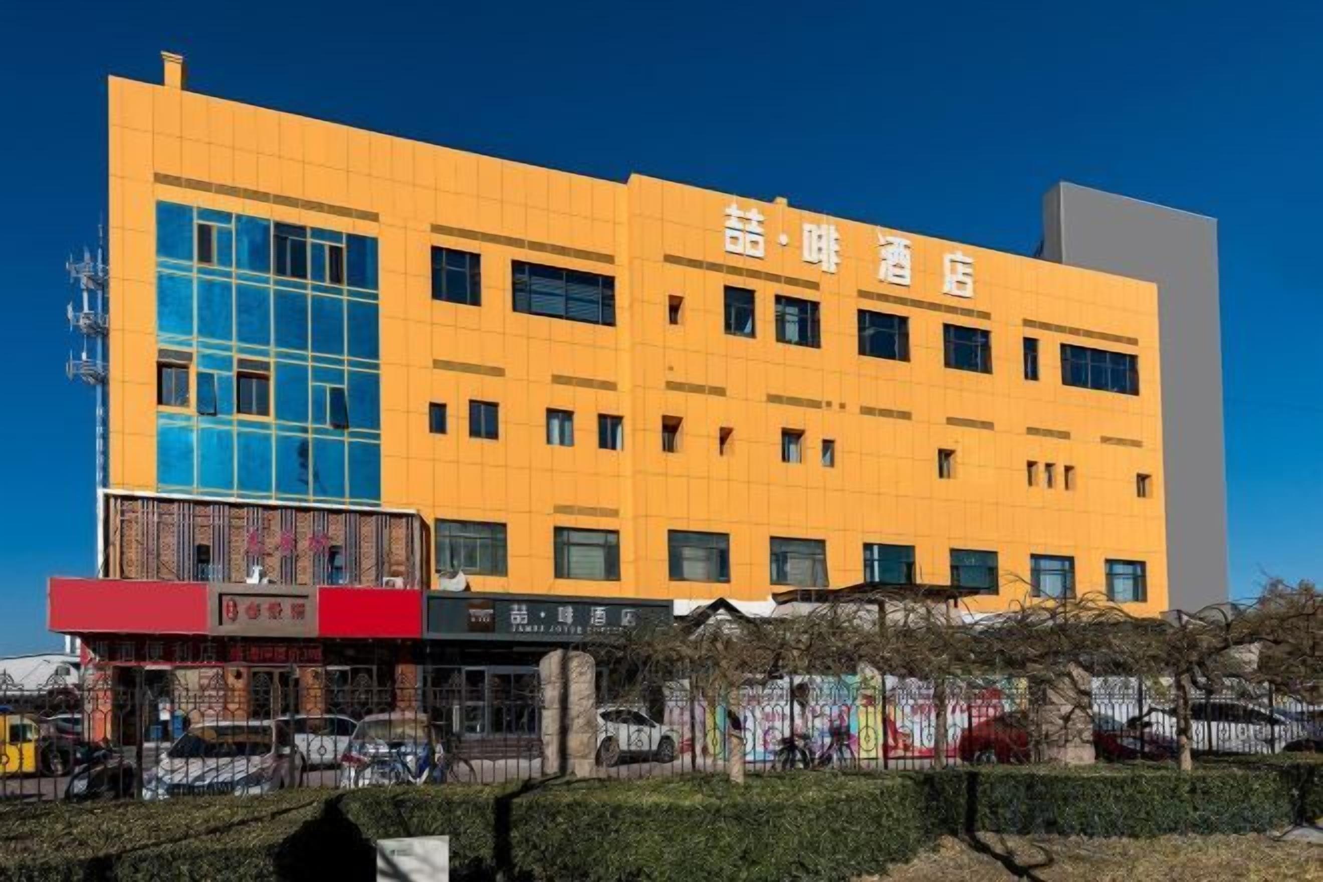 A multi-story building with a yellow facade and large windows.