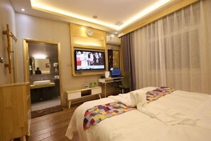 A hotel room with a bed, a TV, a desk with a computer, a mirror, and a bathroom visible through an open door. - Xinzheng Venice Fashion Hotel (Xinhua Road Zhonghua Road) (Xinzheng)
