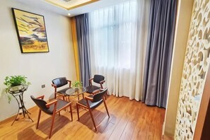 Ein Zimmer mit Holzboden, einem runden Tisch mit Stühlen, einer kleinen Pflanze und einem Gemälde an der Wand.