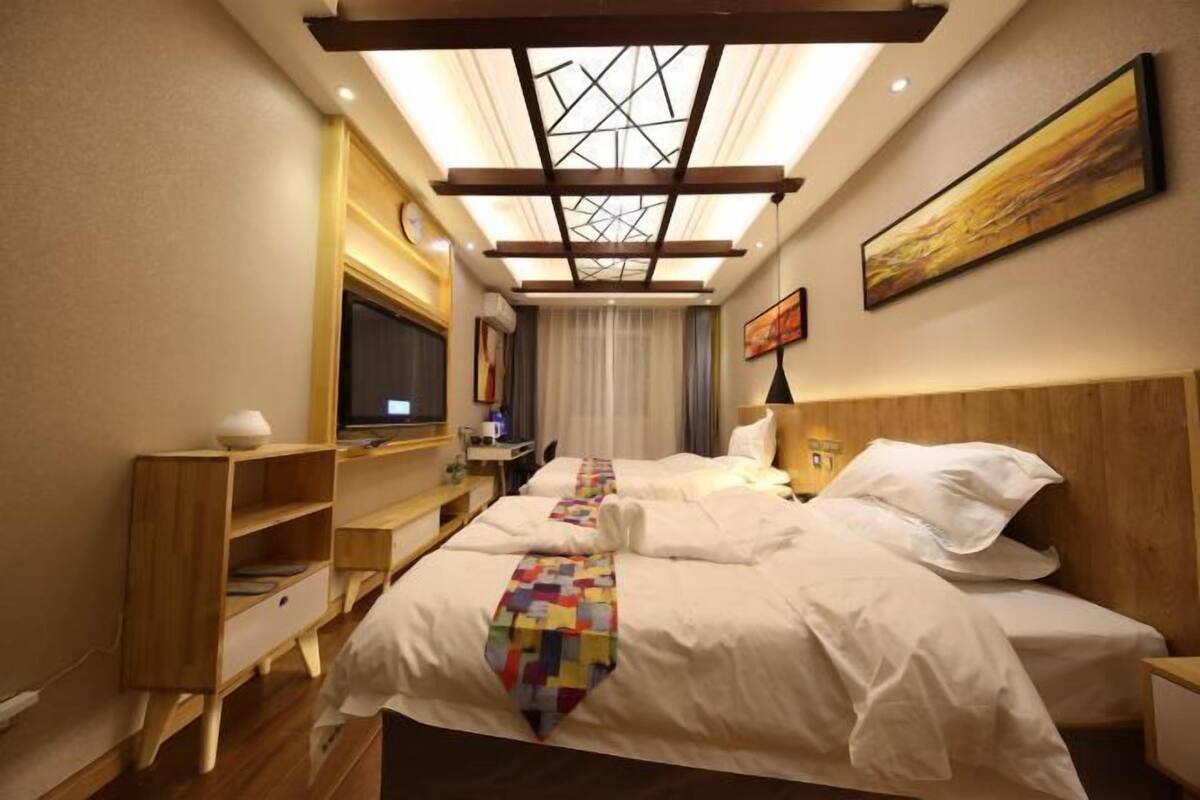 Ein Hotelzimmer mit zwei Betten, einem Fernseher, einem Schreibtisch und einem Oberlicht.