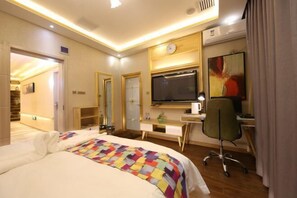 A hotel room with a bed, a desk with a computer, a chair, a TV, and a clock on the wall. - Xinzheng Venice Fashion Hotel (Xinhua Road Zhonghua Road) (Xinzheng)