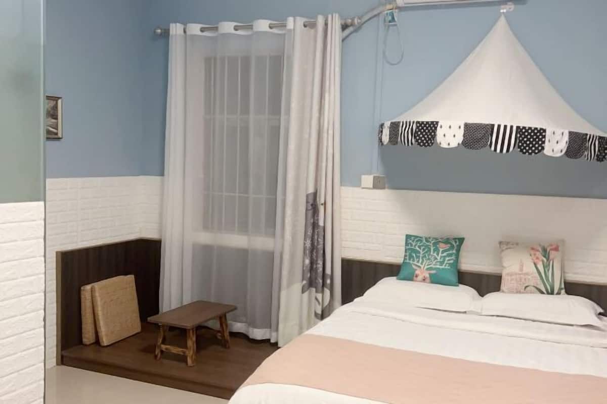 A bedroom with a bed, a bench, a shower curtain, and a canopy.