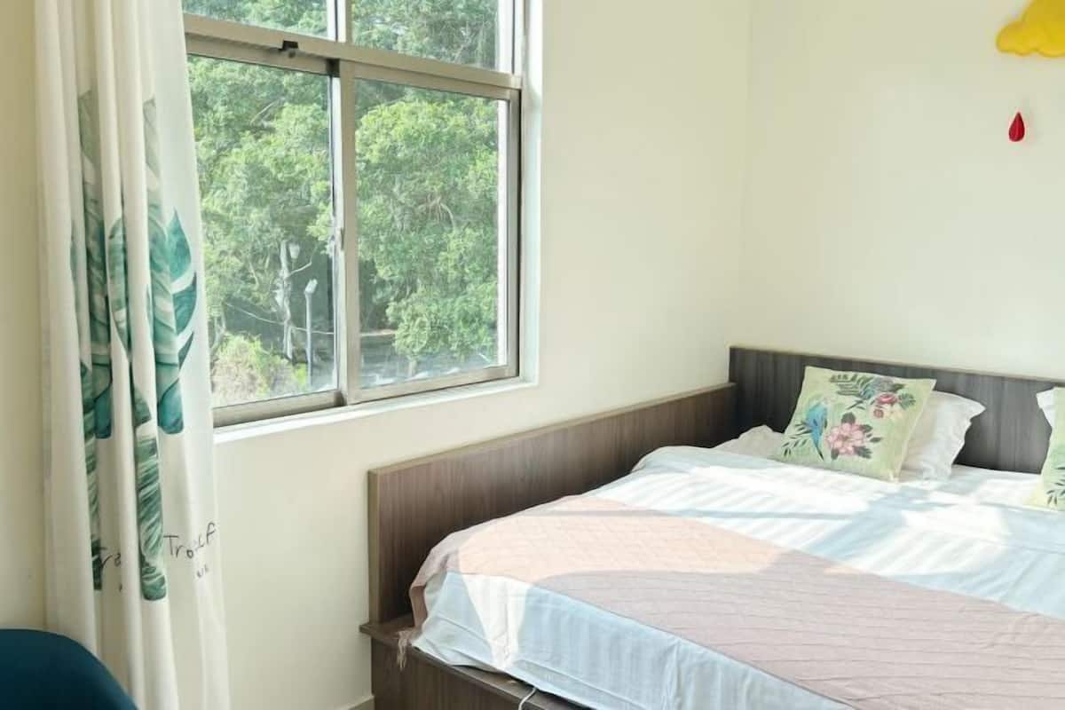 A bedroom with a bed, a window, and a view of trees.