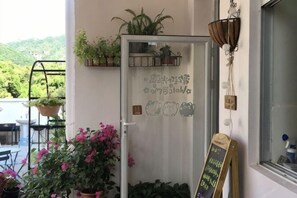 A glass door with a metal basket, potted plants, and a chalkboard sign.
