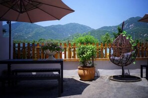 A patio with a table, an umbrella, a hanging chair, and potted plants. - Yingyuge Inn (Shenzhen)