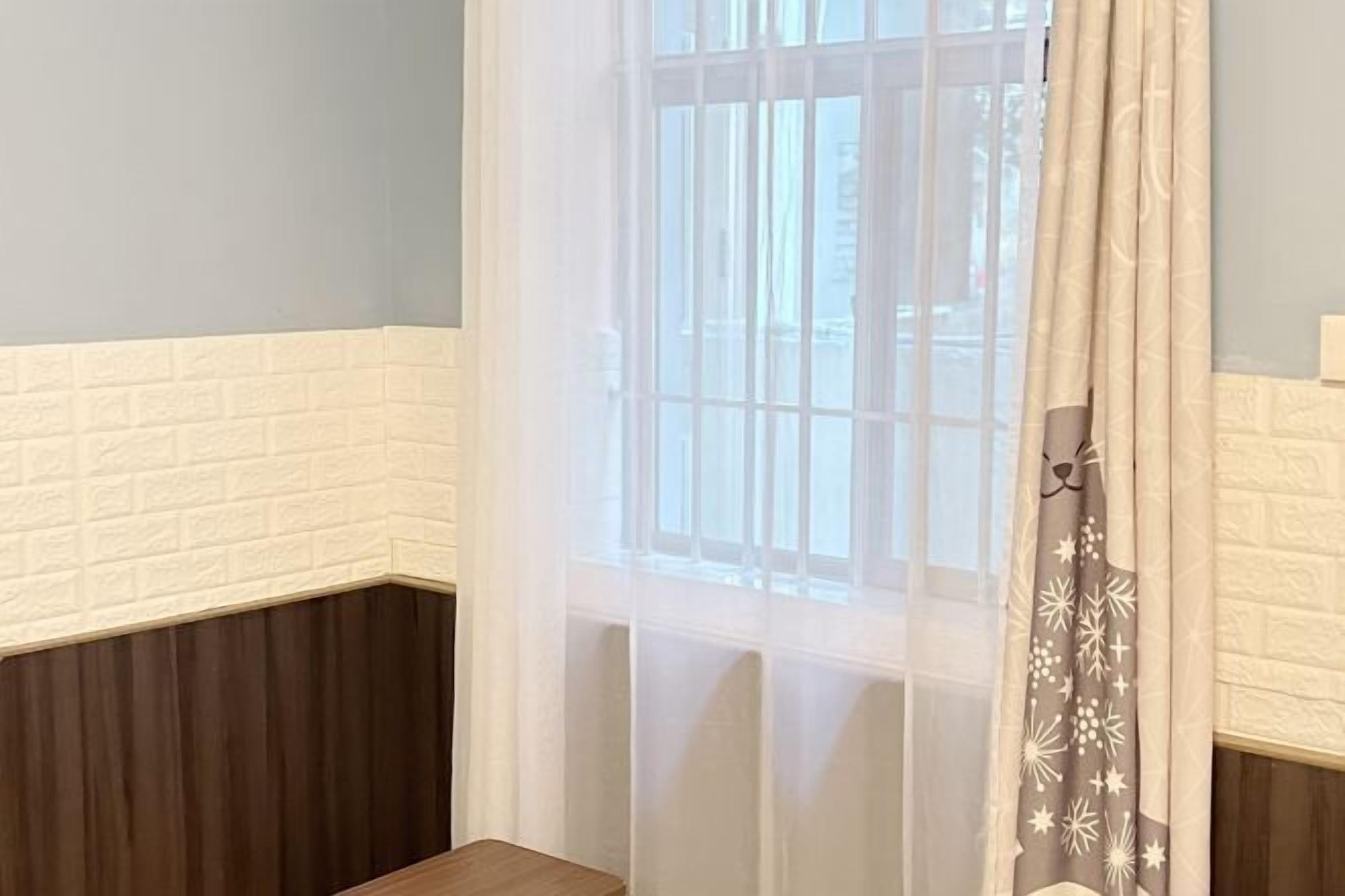 Una habitación con ventana, pared de ladrillo blanco y un banco de madera.