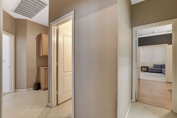 Un couloir avec une porte donnant sur une pièce où se trouvent un canapé et une petite table.