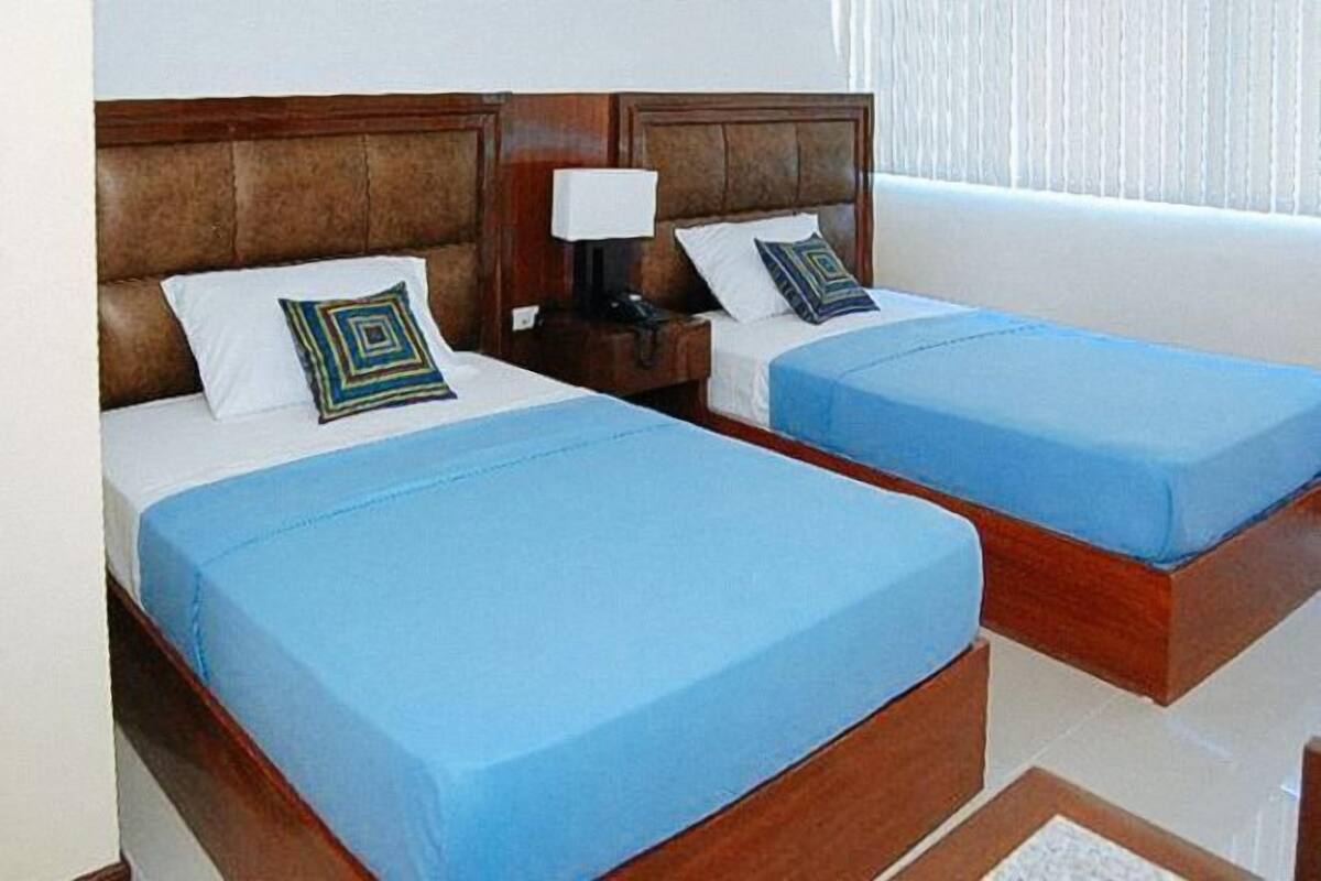 Two single beds with wooden headboards, blue bedding, and decorative pillows.