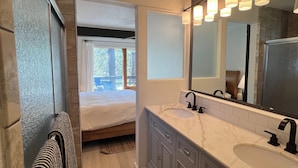 Un baño moderno con un lavamanos amplio, un espejo y una zona de ducha.
