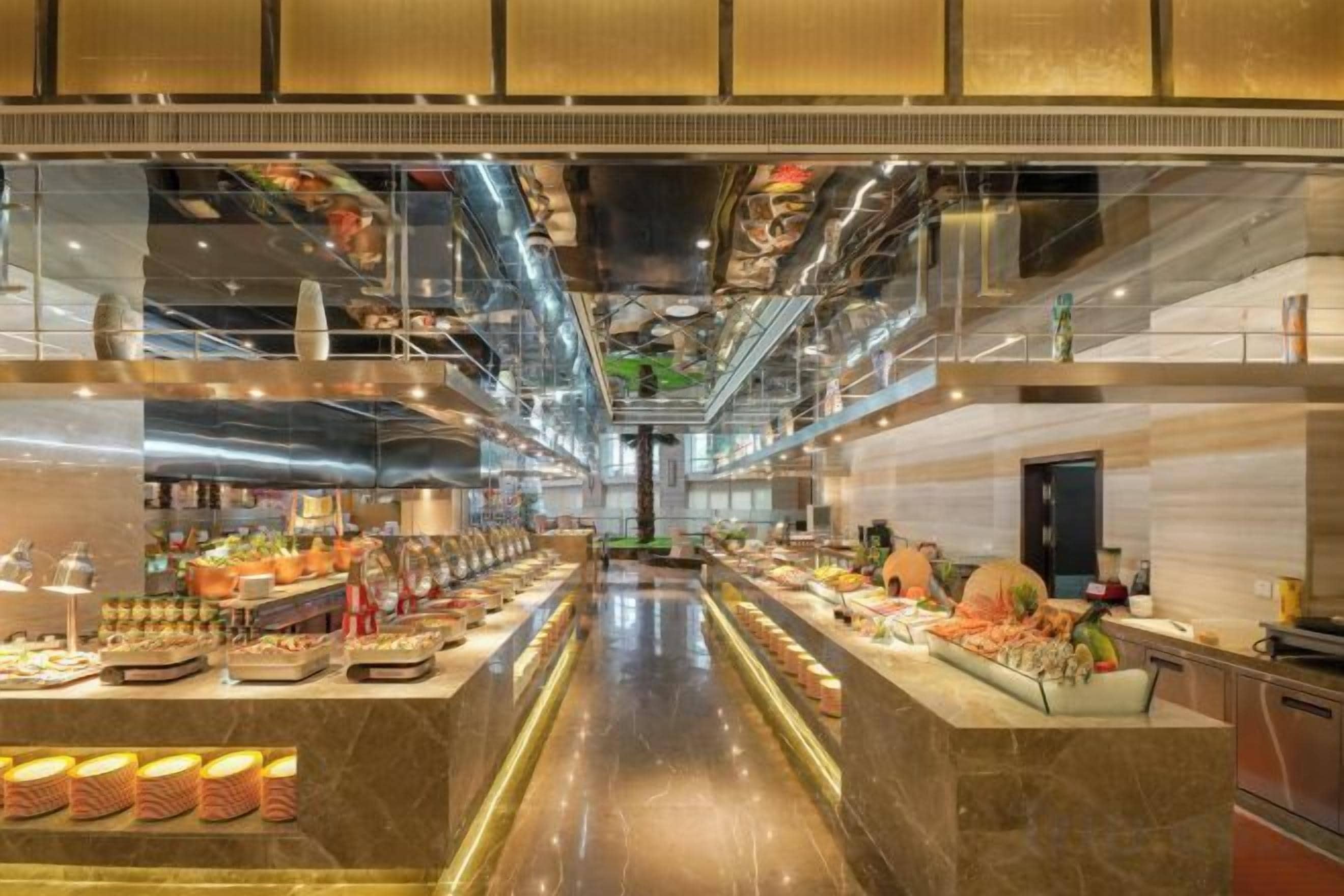 Una cocina de hotel moderna con electrodomésticos de acero inoxidable, una encimera de mármol y una variedad de alimentos a la vista.