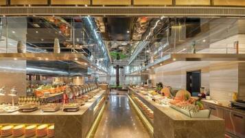 Una cocina de hotel moderna con electrodomésticos de acero inoxidable, una encimera de mármol y una variedad de alimentos a la vista.