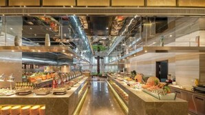 Un vaste espace buffet avec une allée centrale, entouré de différents stands de restauration.