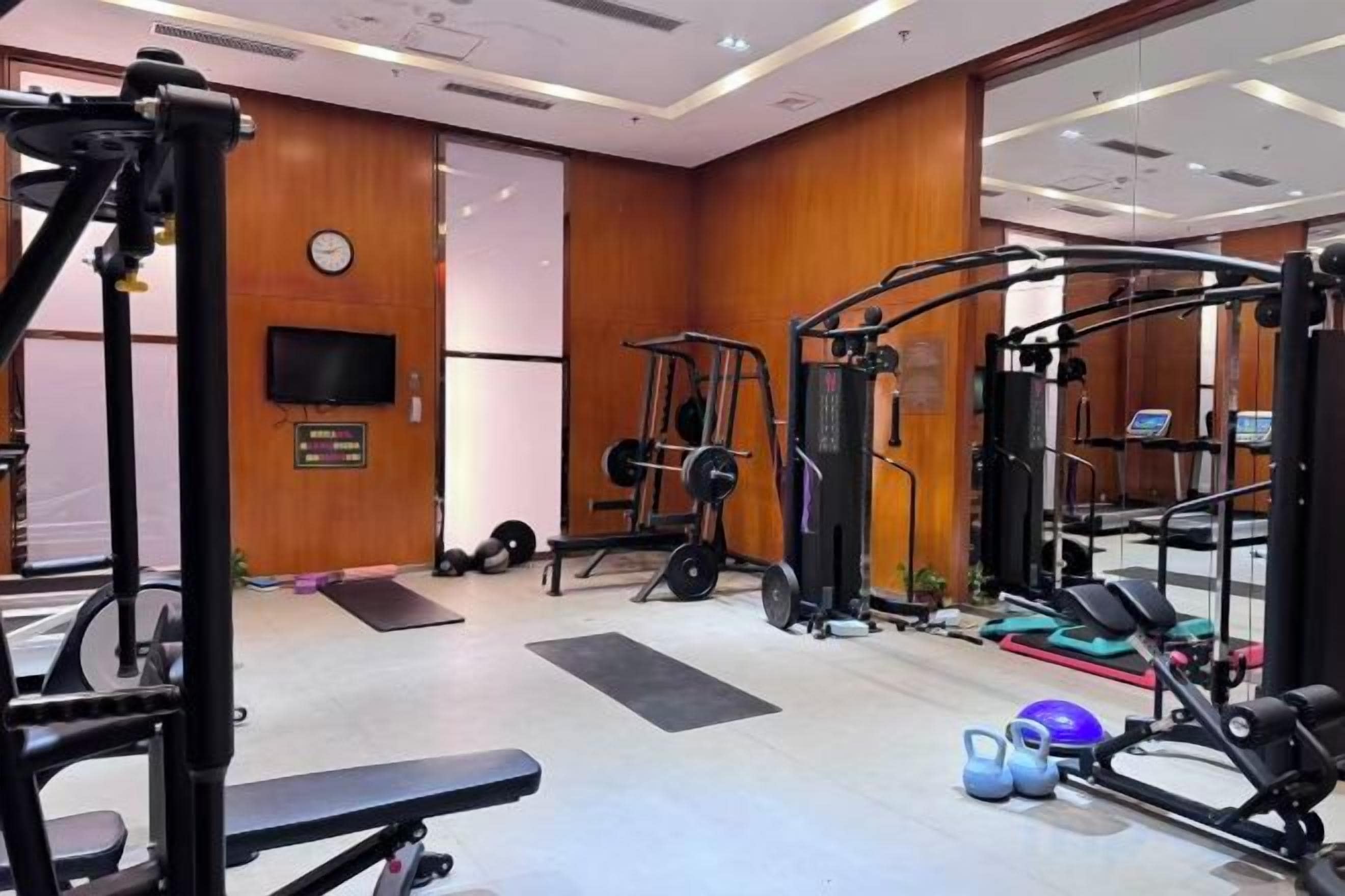 A gym with various exercise equipment, including a bench, weight machines, and a treadmill.