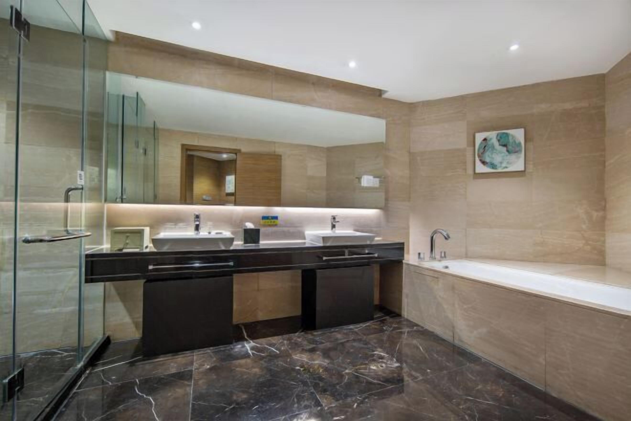 A modern bathroom with a glass shower enclosure, a double sink vanity, and a standalone bathtub.