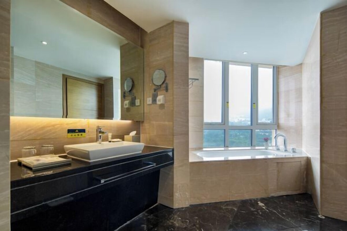 Un bagno moderno con uno specchio grande, due lavabi, una vasca da bagno e una finestra che offre luce naturale.