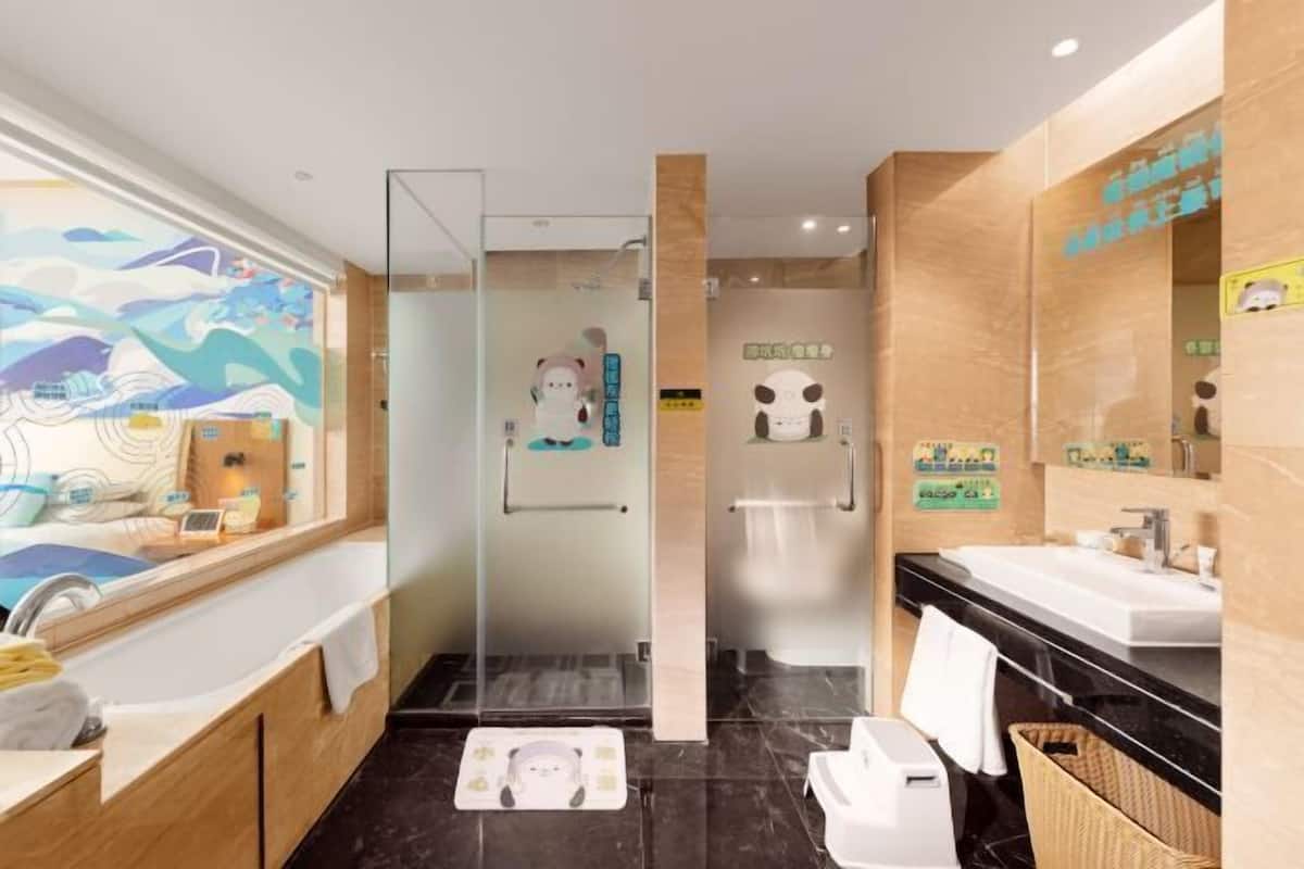 Een moderne badkamer met een glazen douchecabine, een grote spiegel en een vloer van zwart marmer.