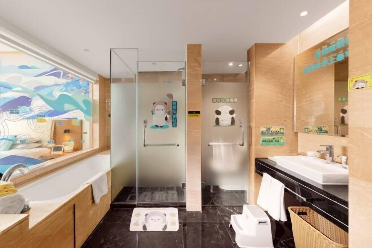 A modern bathroom with a glass shower enclosure, a large mirror, and a black marble floor.