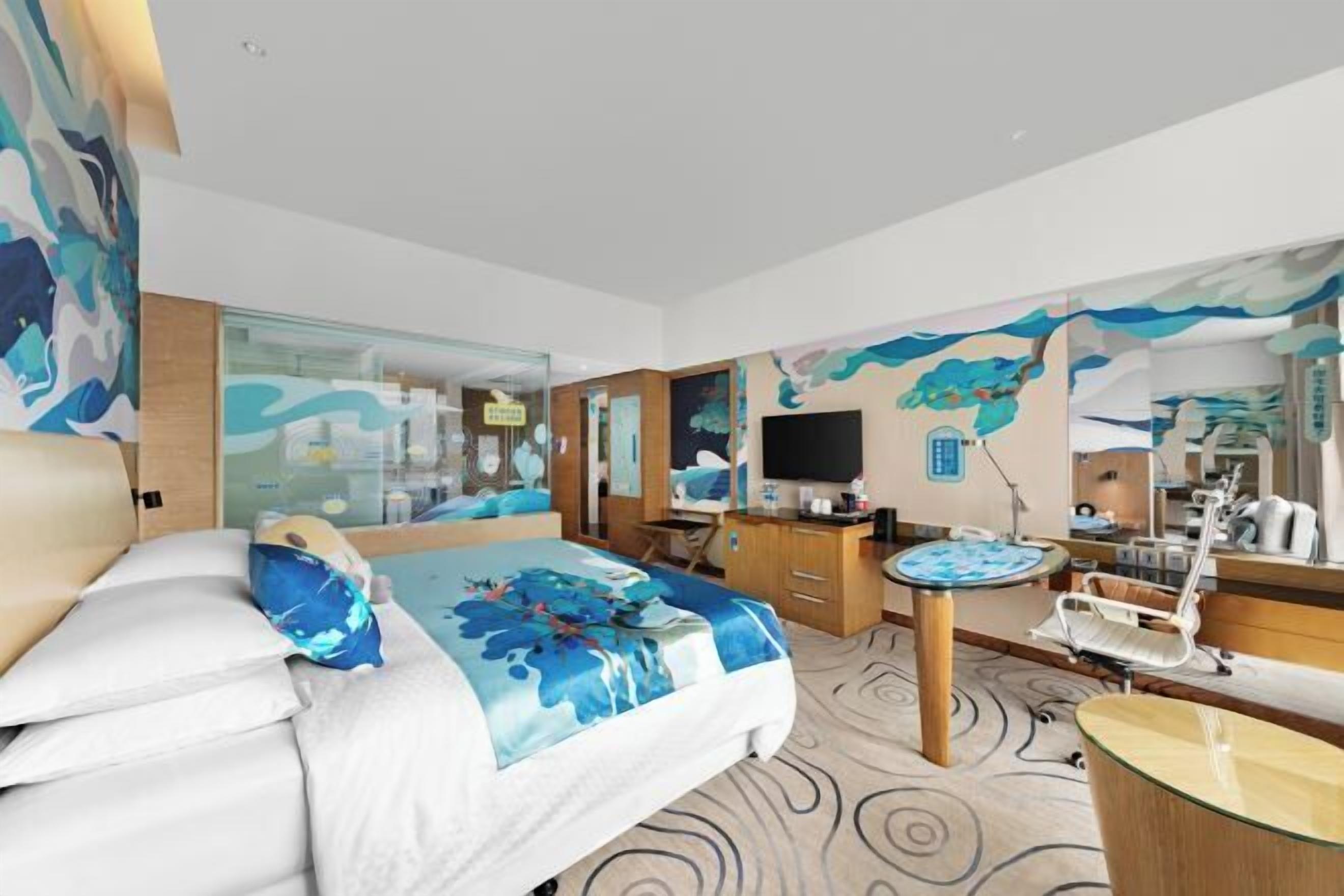 Ein Hotelzimmer mit Bett, Schreibtisch, Stuhl, Fernseher und Bad.