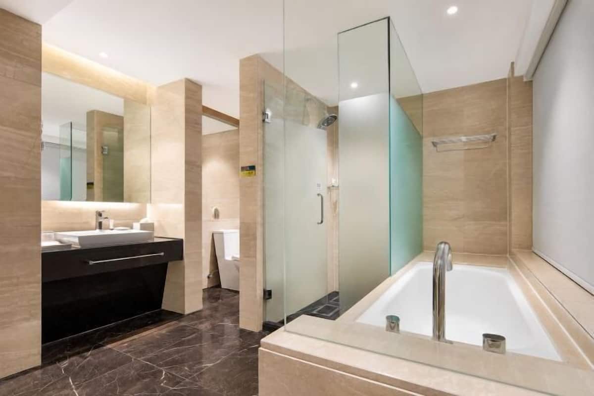 Een moderne badkamer met een douchecabine van glas, een vrijstaand bad en een wastafel met spiegel.