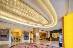 A spacious lobby with a curved ceiling, marble flooring, and a reception desk.