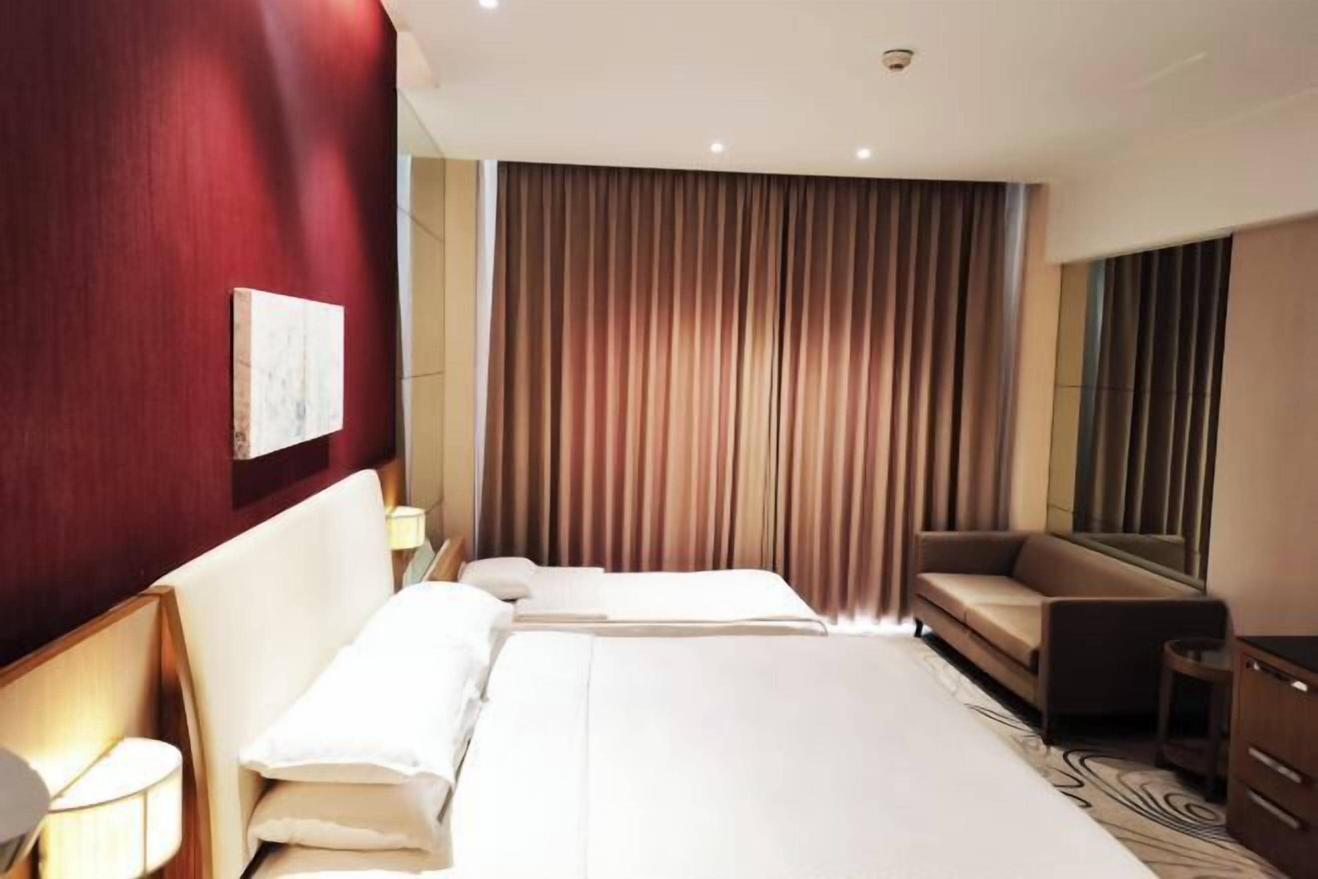 Ein Hotelzimmer mit einem großen Bett, einer Couch, einem Schreibtisch und einem Spiegel.